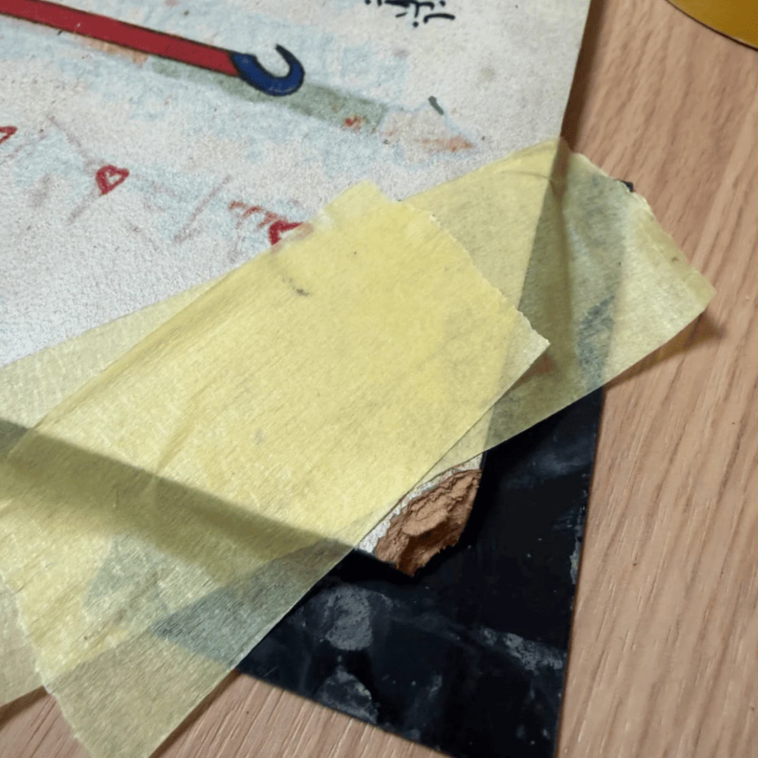 Damaged corner of an exhibition manuscript display protected with masking tape