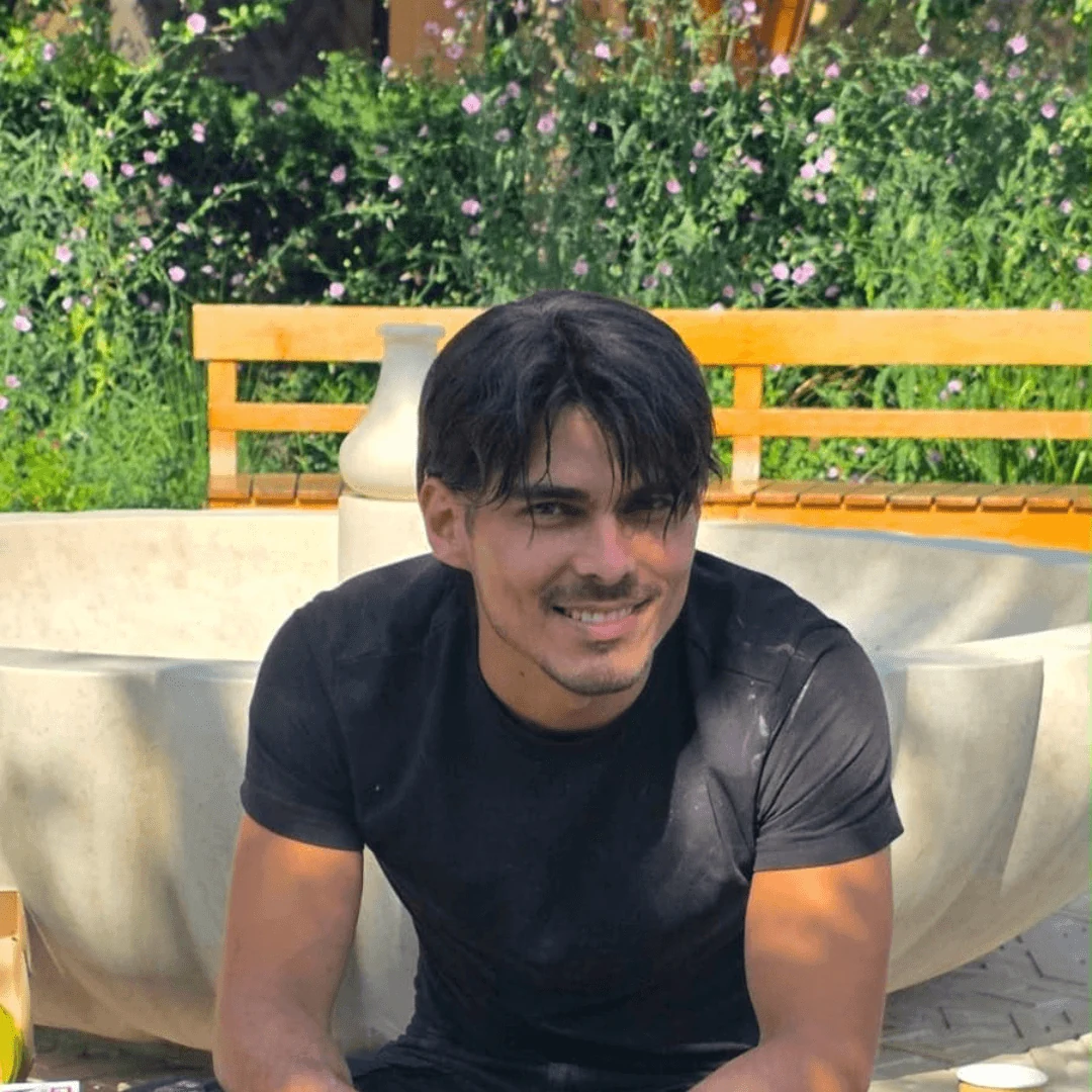 Eliel, co-founder of Surface Artists, sitting in front of the restored limestone fountain at Cambridge Central Mosque